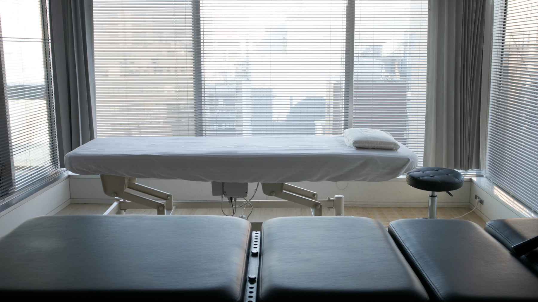 Treatment room at the Ebisu clinic in Tokyo: an osteopathy table by the windows, with a chiropractic drop table in the foreground.